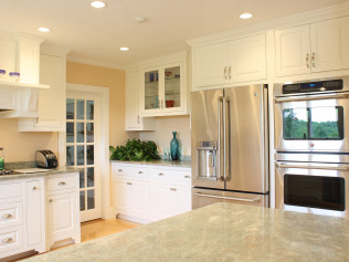 White kitchen with stainless steel appliances, white cabinets, and a light-colored countertop.