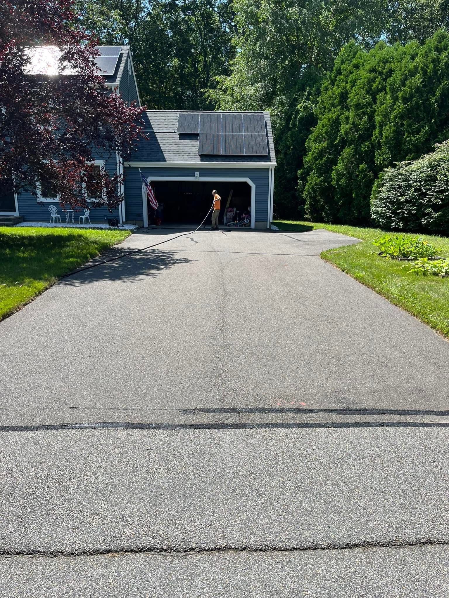 A person stands in a dark garage at the end of a paved driveway, holding a line connected to the ground.