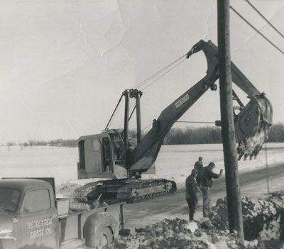 A black and white photo of an excavator with a license plate that says crest on it