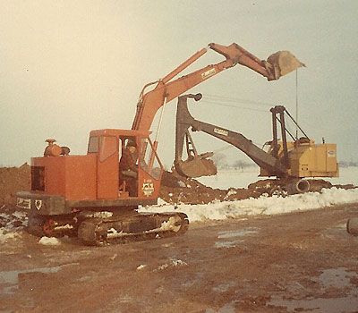 A man is driving a red excavator in a snowy field