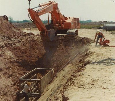 A large orange excavator is digging a hole in the dirt