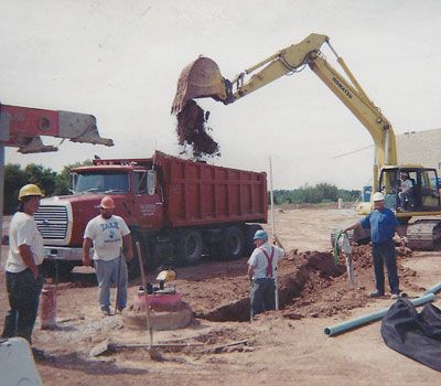 A yellow excavator is loading dirt into a dump truck