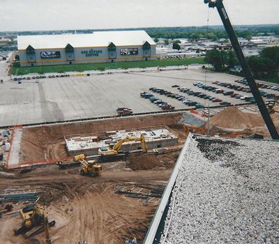 An aerial view of a construction site with a large building in the background