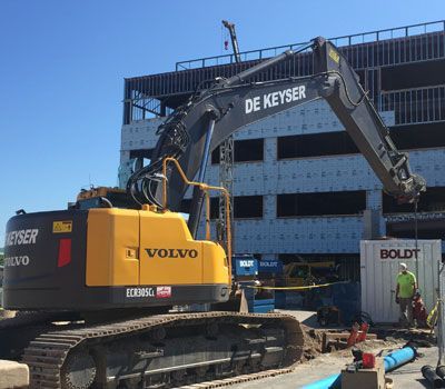 A volvo excavator is parked in front of a building under construction