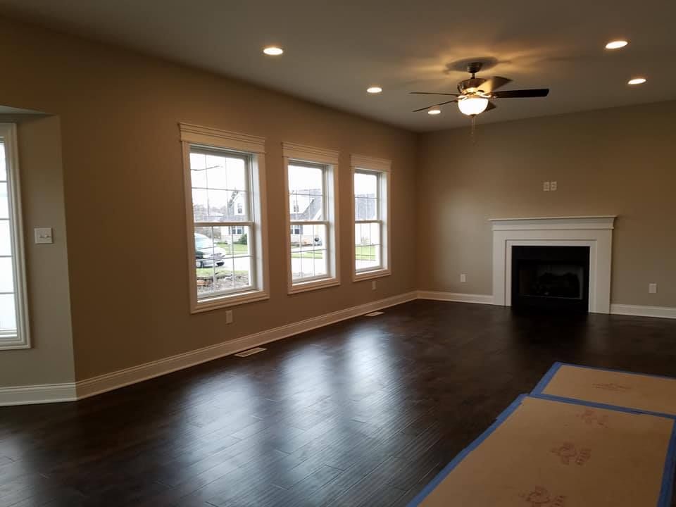 an empty living room with a fireplace and ceiling fan