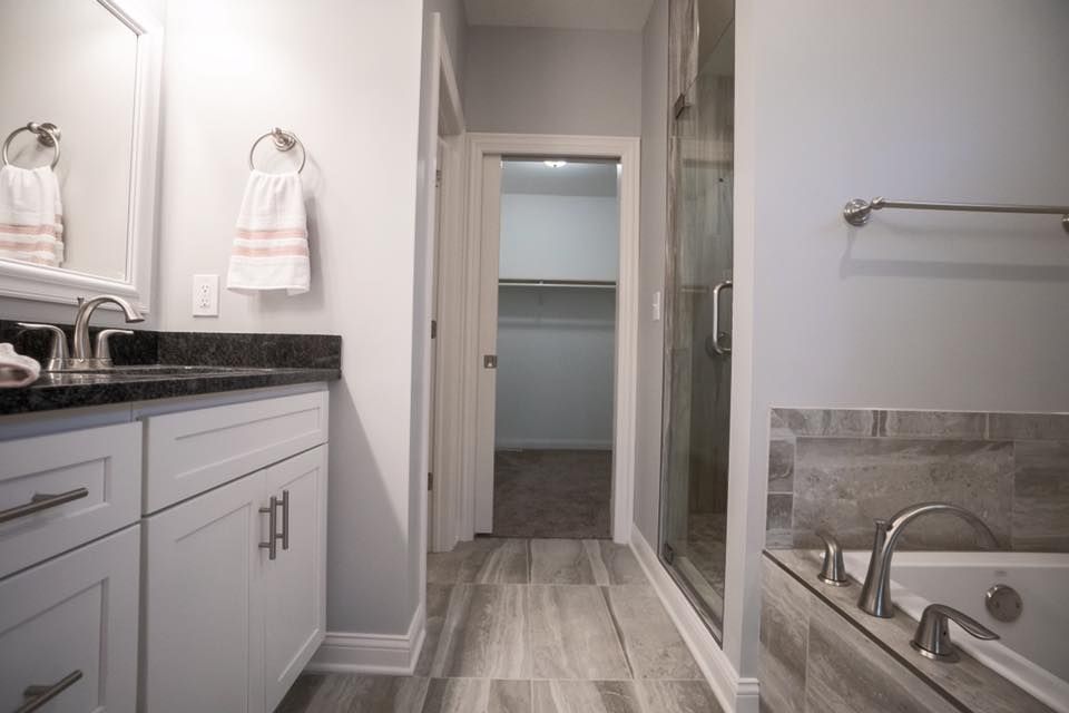 a bathroom with a tub , sink , mirror and walk in closet .