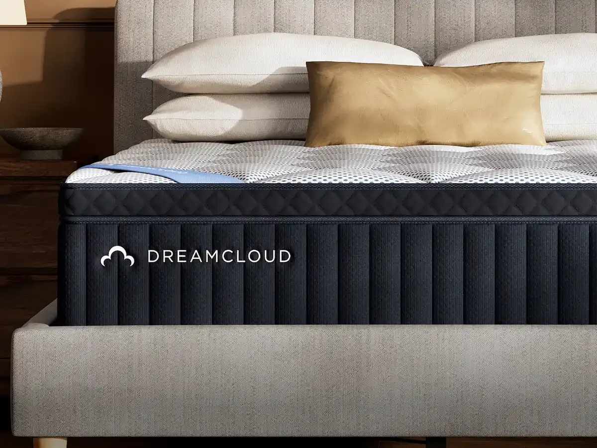 DreamCloud mattress on a bed with white pillows and a tan bolster in a bedroom