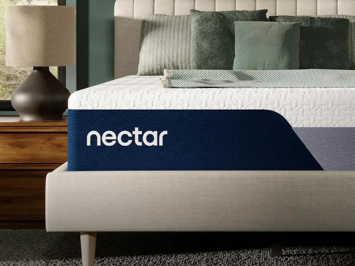 Neatly made bed with a dark blue Nectar mattress label in a modern bedroom