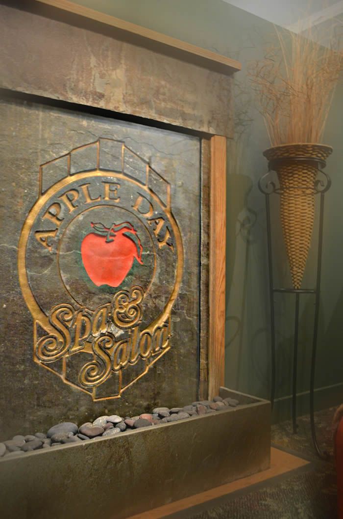 Water fountain with Apple Day Spa logo and tall wicker vase.
