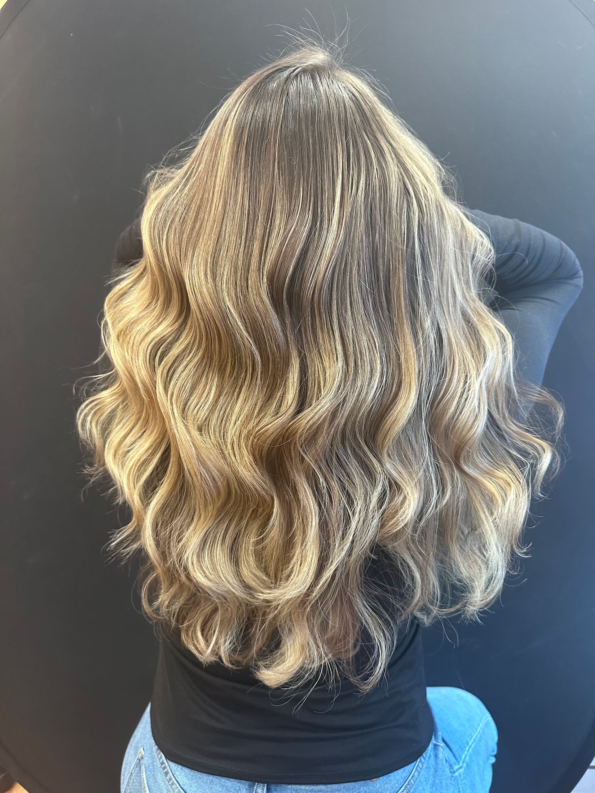 Woman's long, wavy hair. Blonde and brown highlights, against a black background.