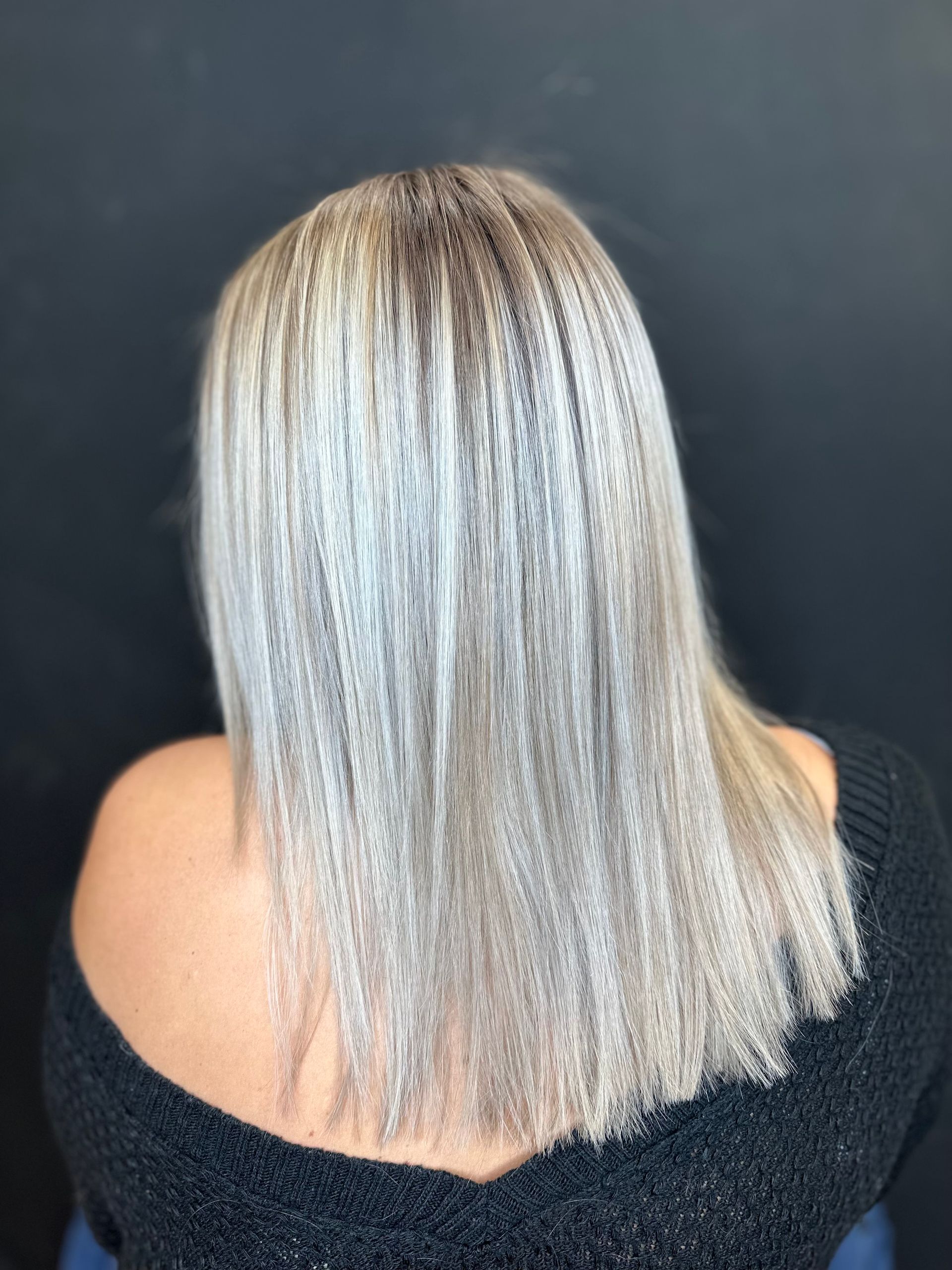 Woman with platinum blonde hair, styled with crimped texture, against a dark background.