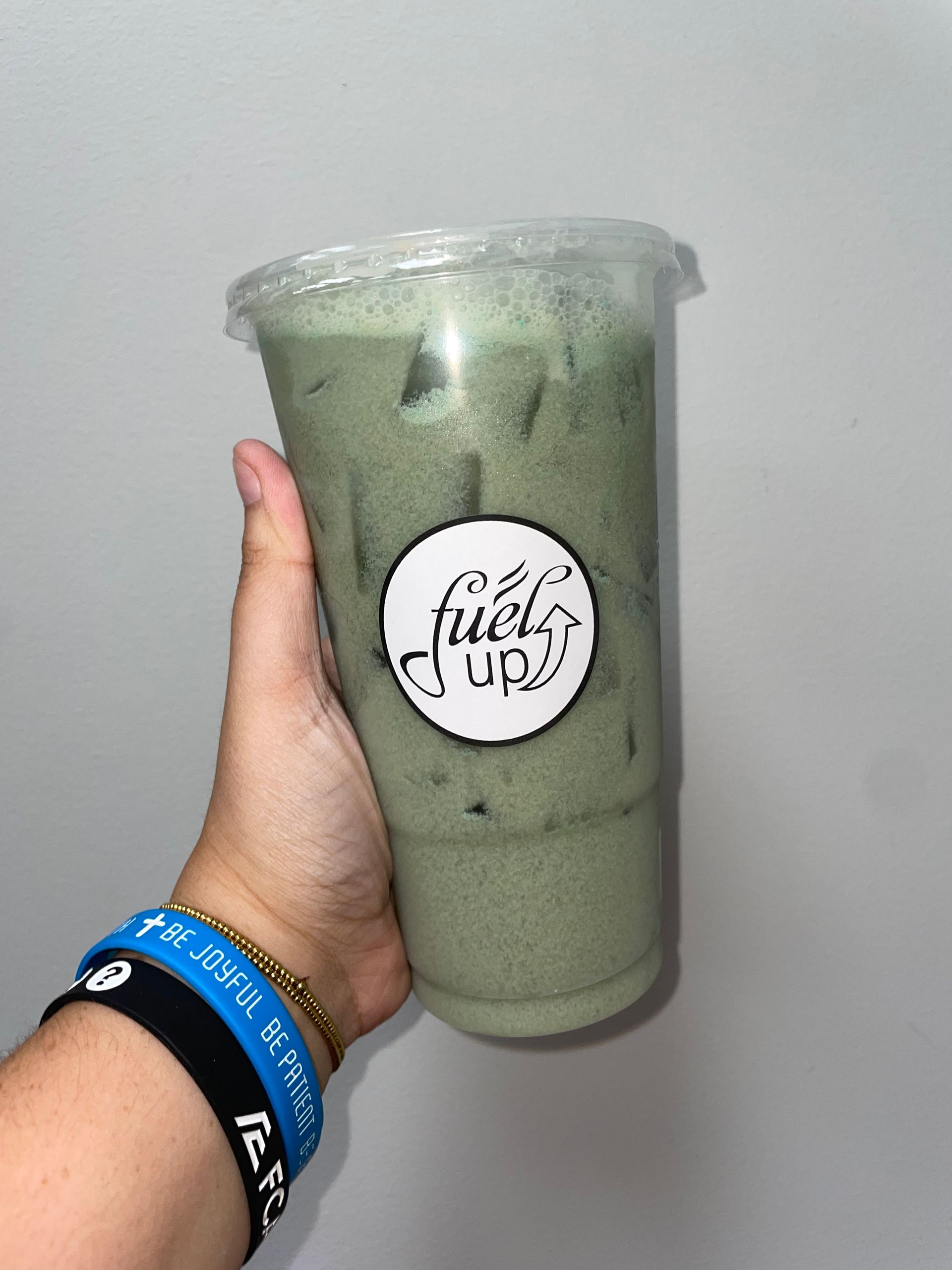 A person is holding a cup of green liquid that says fuel up