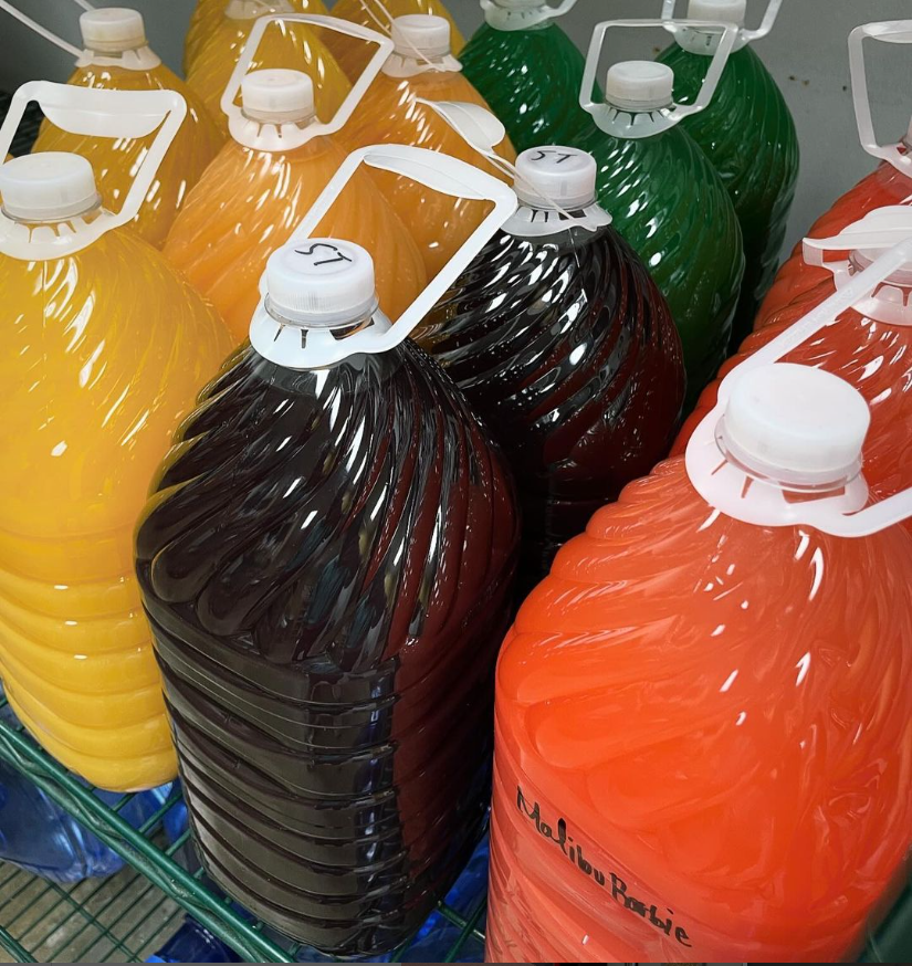 Several gallon bottles of juice are lined up on a shelf