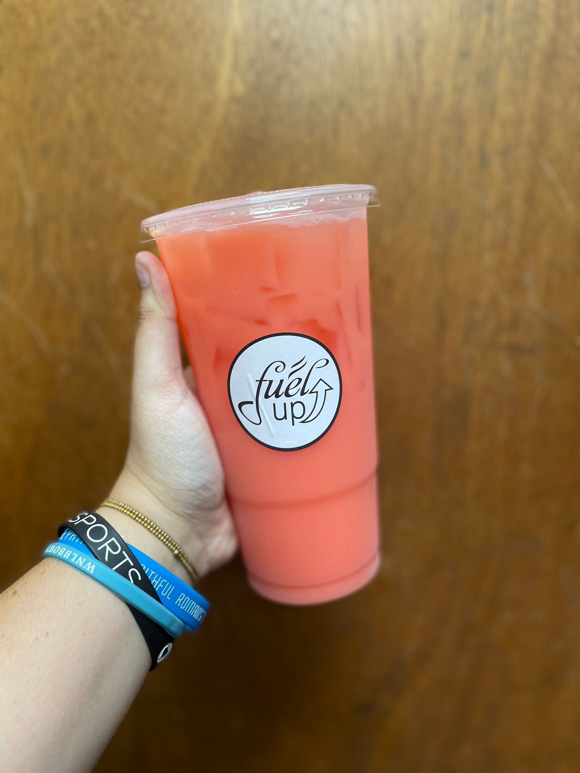 A person is holding a pink drink in their hand.