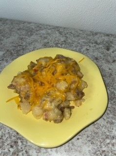A yellow plate topped with potatoes and cheese on a table.