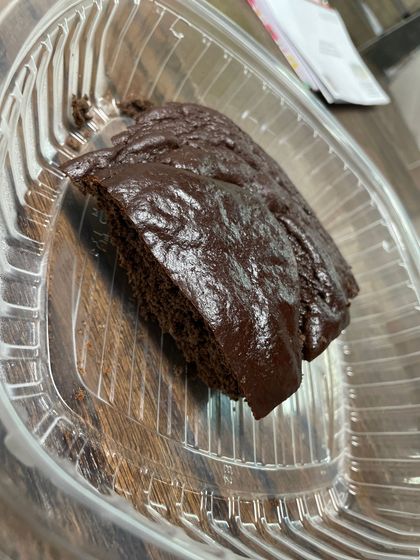 A piece of chocolate cake is in a plastic container.