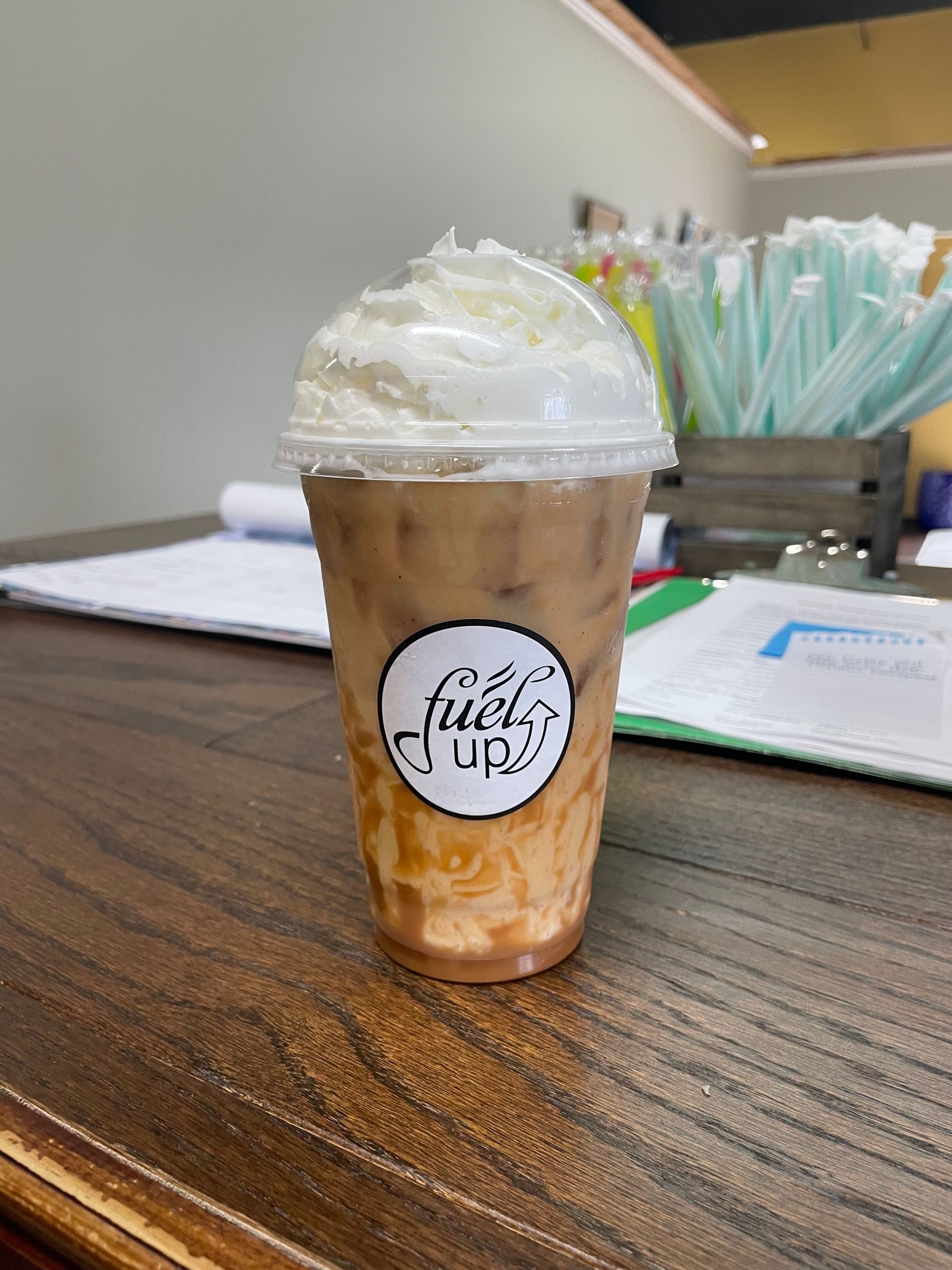 A cup of coffee with whipped cream on top is sitting on a wooden table.