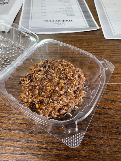 A close up of a cookie in a plastic container on a wooden table.