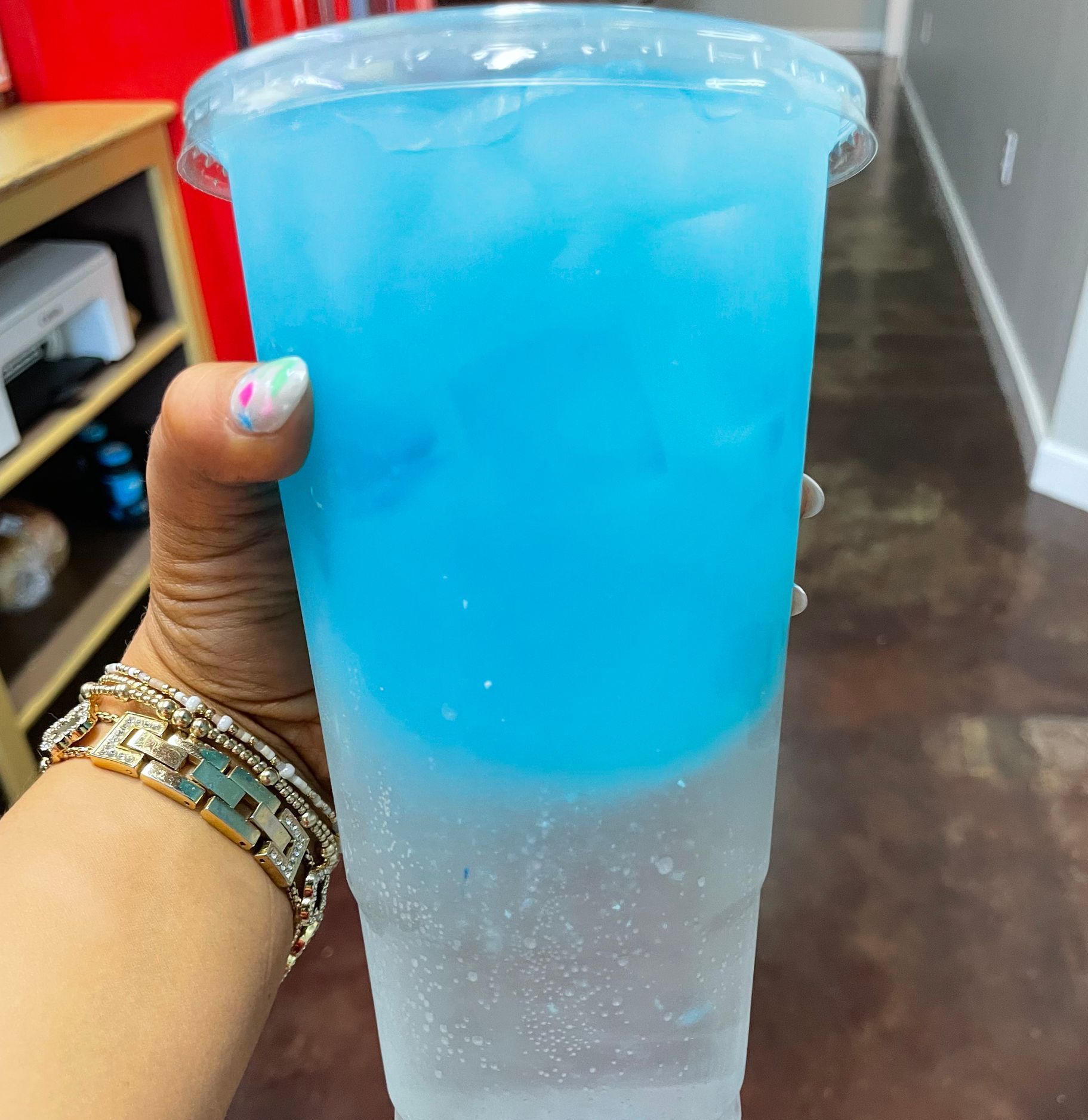 A person is holding a blue drink in a plastic cup