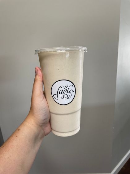 A person is holding a cup of milkshake in their hand.