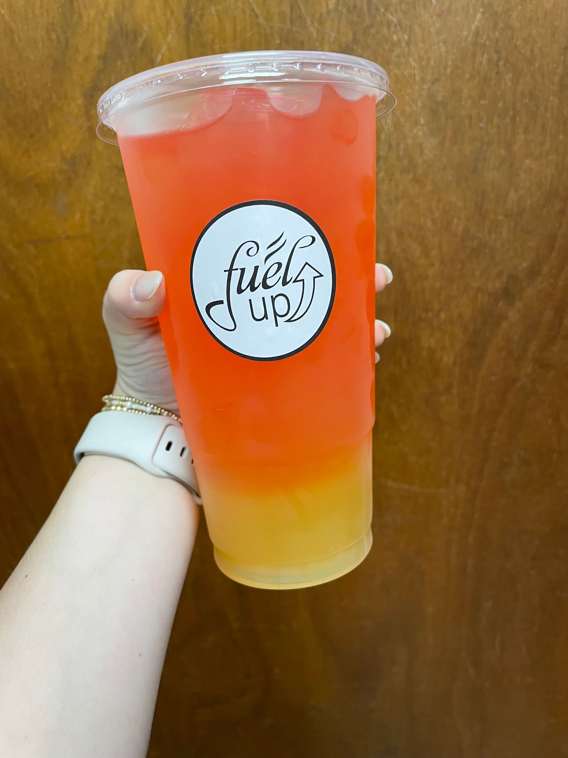 Person holding an orange and yellow drink.