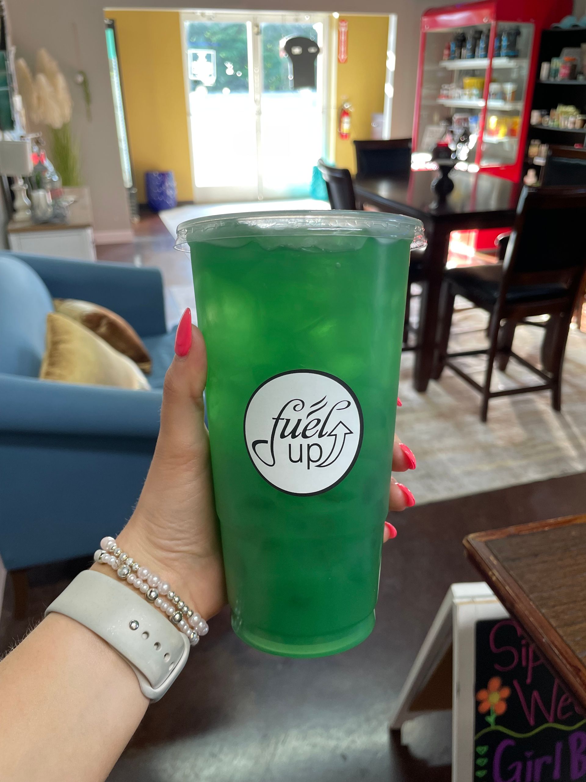 A person is holding a green drink that says fuels up