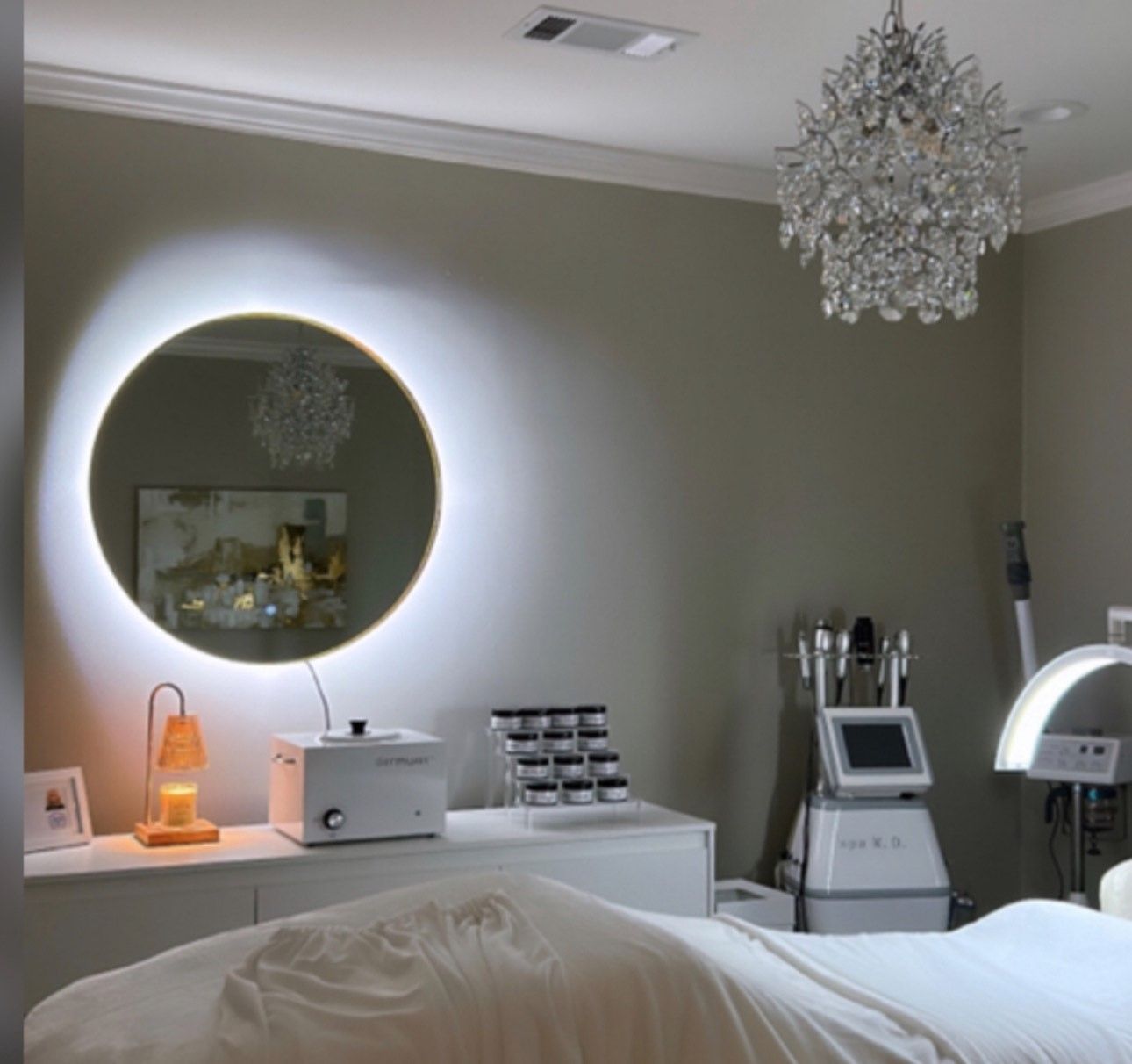 A room with a bed a mirror and a chandelier