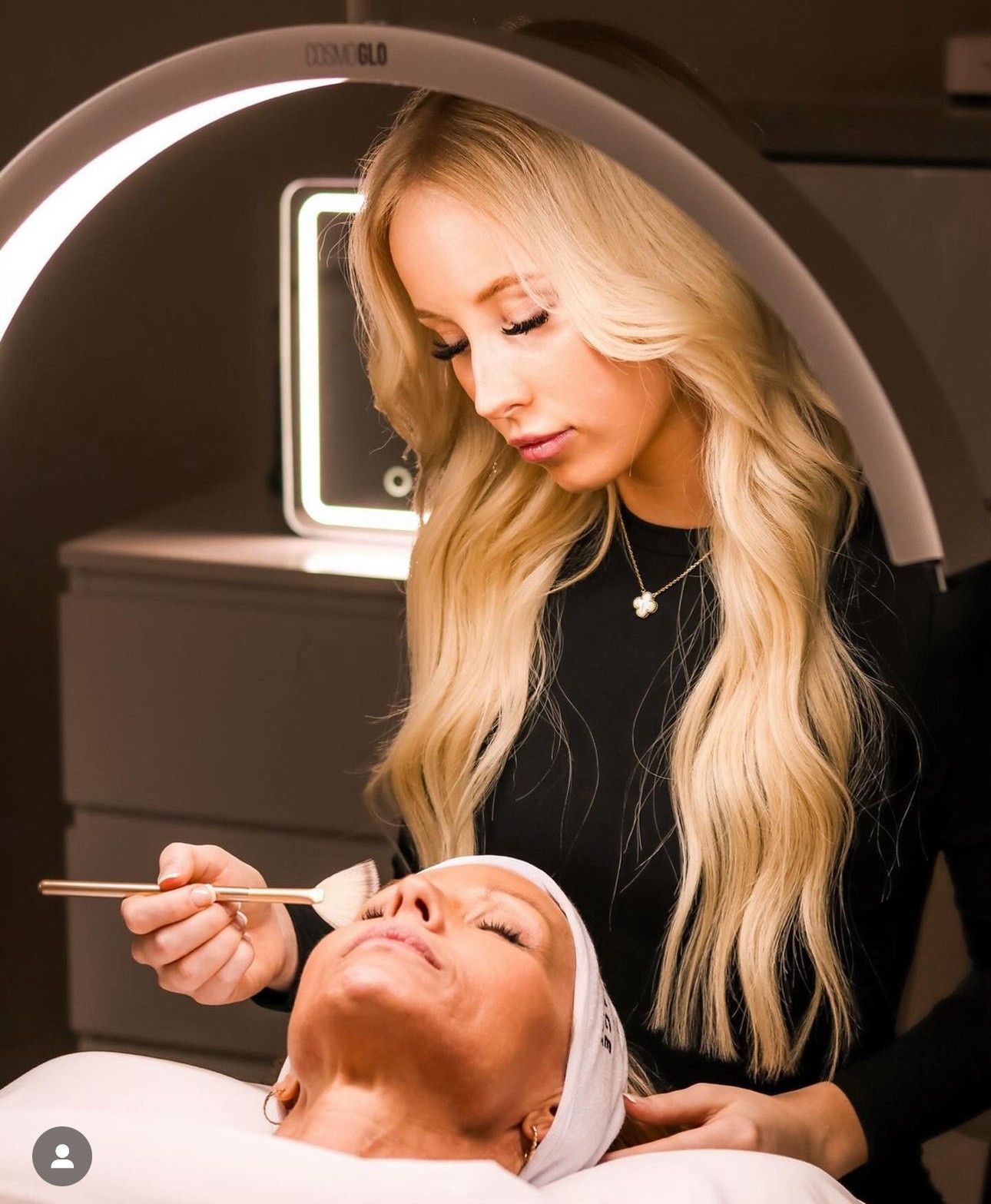 A woman is applying a cream to a woman 's face