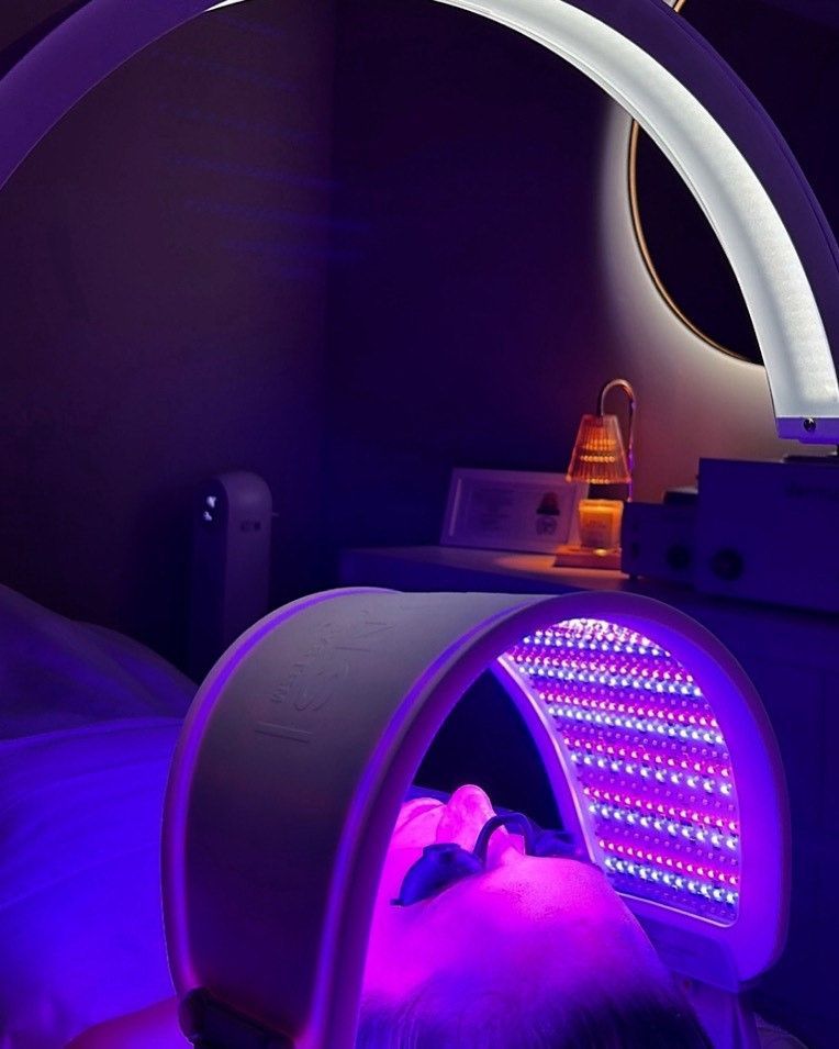 A person is getting a purple light treatment on their face
