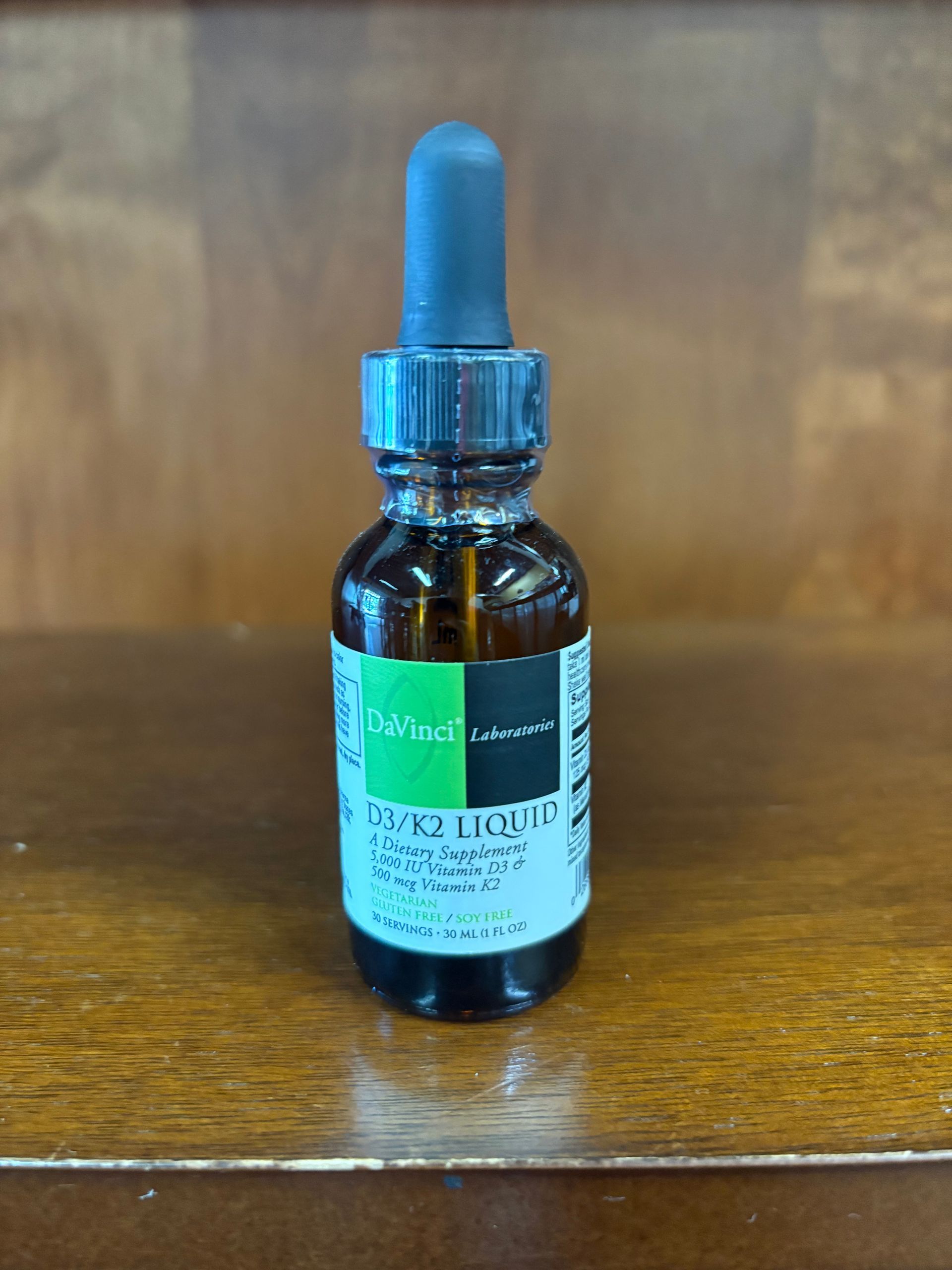 A bottle of liquid is sitting on a wooden table.