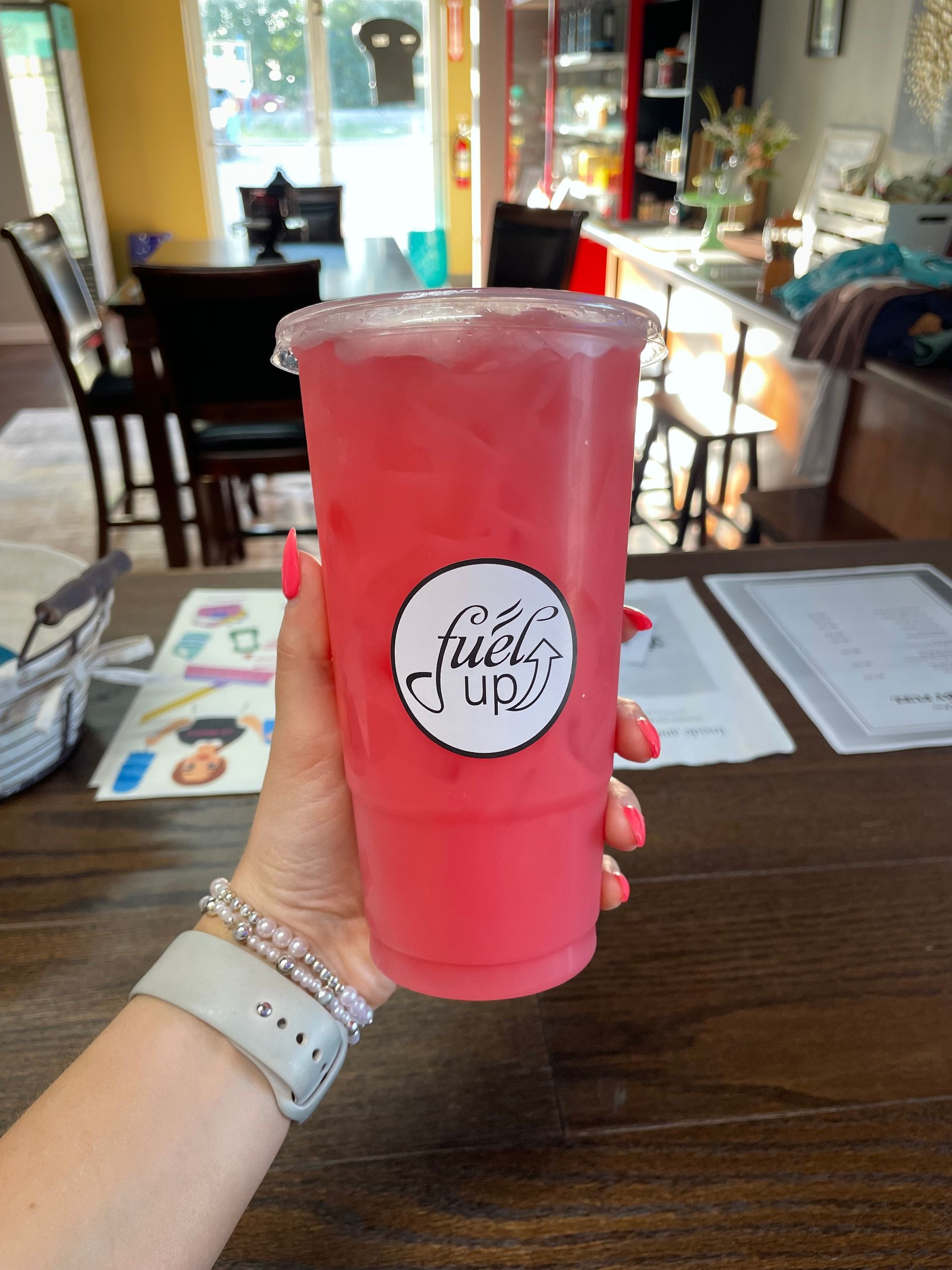 A person is holding a pink smoothie in their hand
