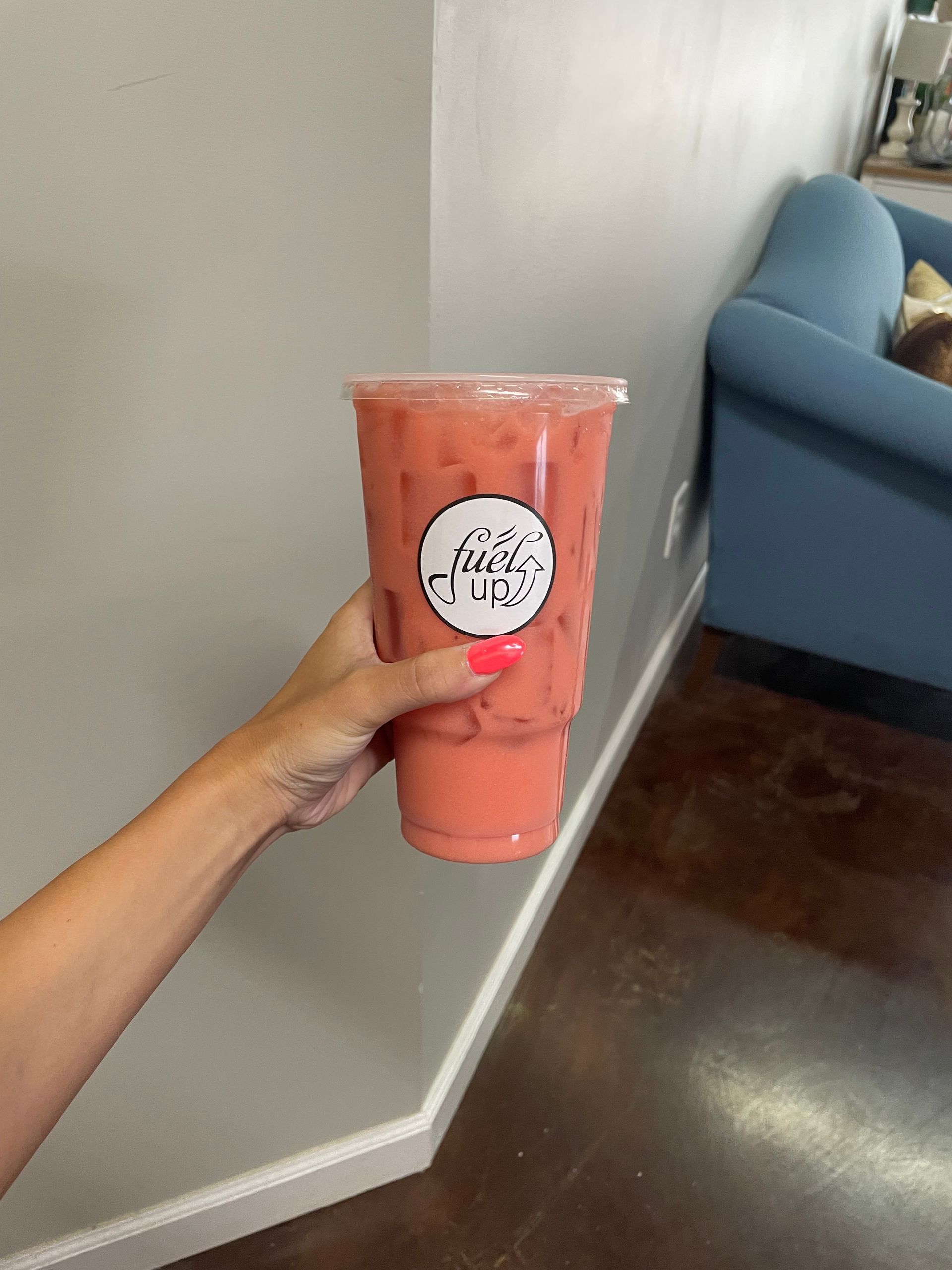 A person is holding a pink drink in their hand.