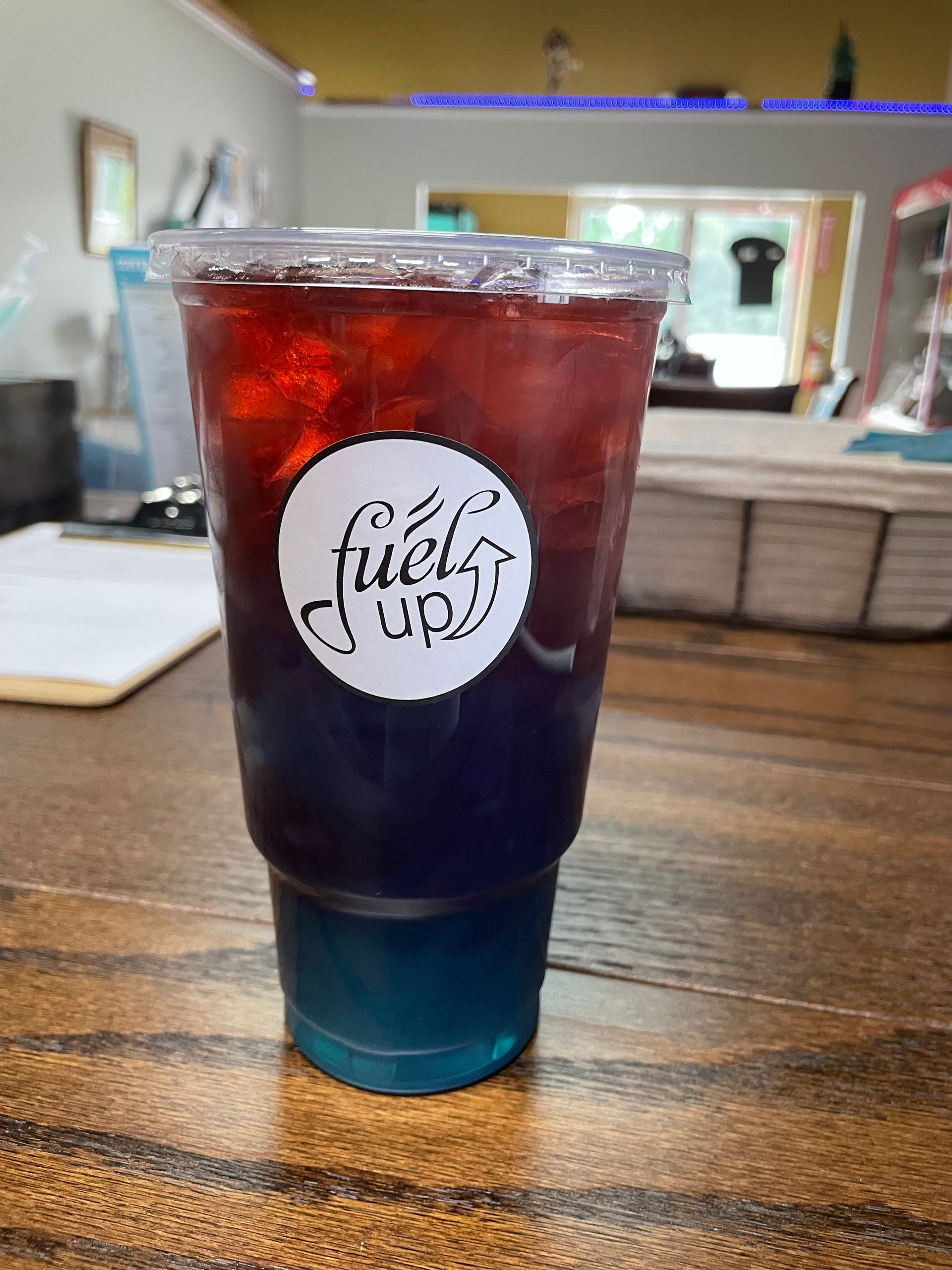 A cup of fuels up iced tea is sitting on a wooden table.