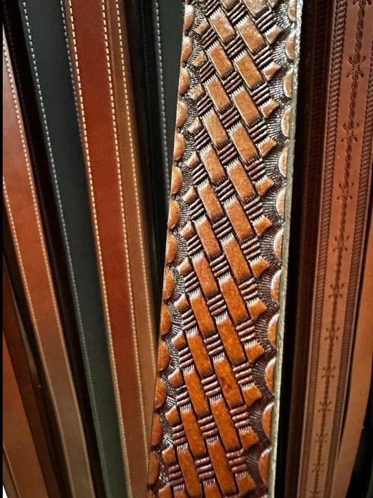 Close-up of decorative leather and woven fabric belts in black, brown, and tan patterns.