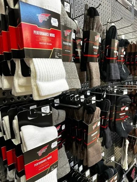 Rows of hanging socks in red, black, gray, and white packaging on a store display shelf