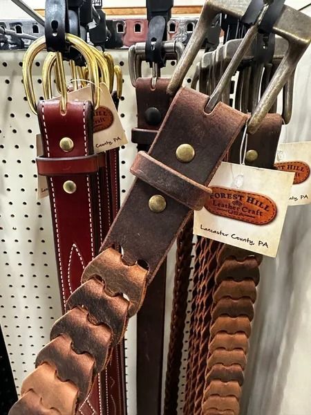 Leather dog collars in red, brown, and tan hanging on a retail display rack
