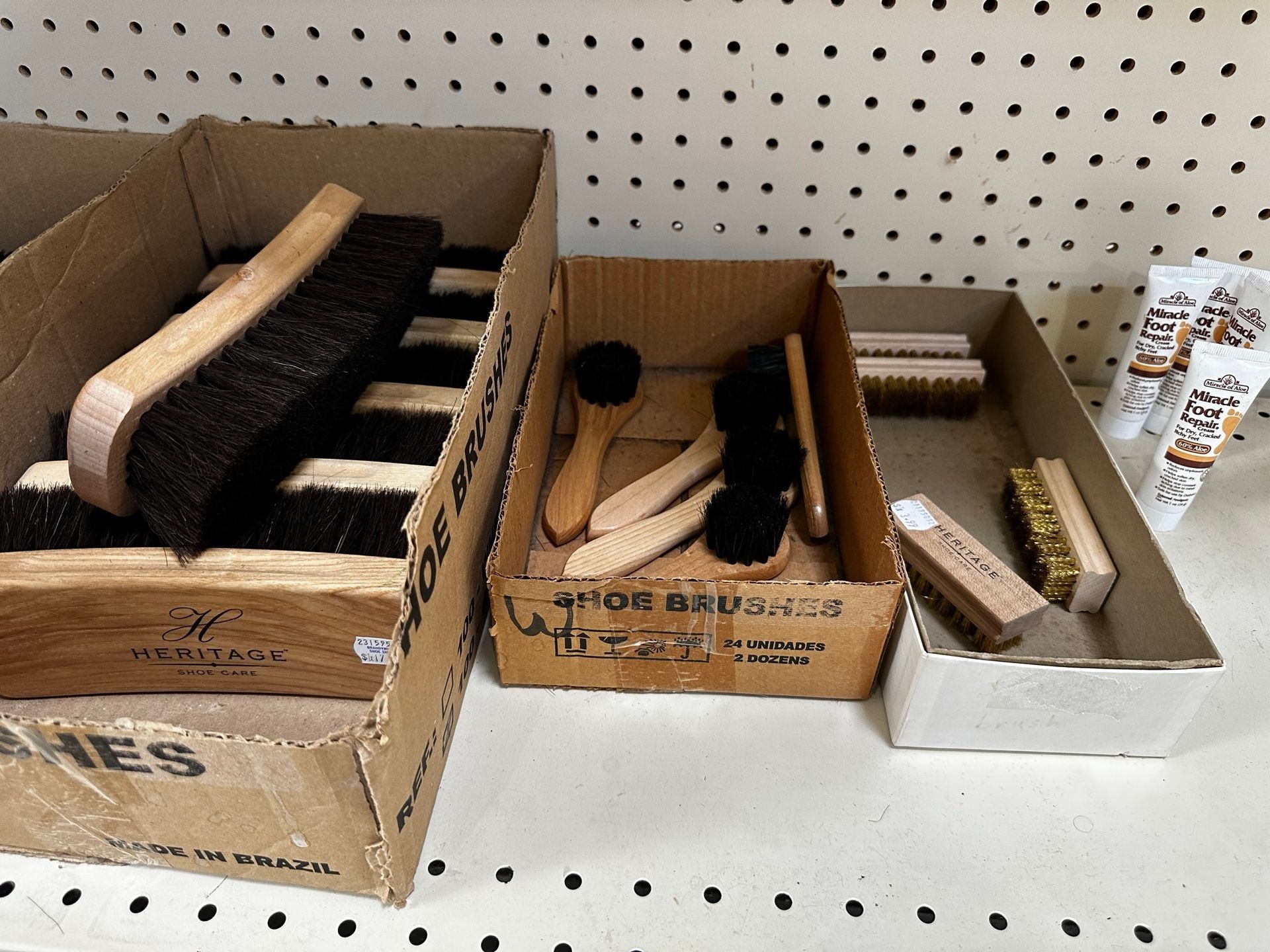 Wooden cleaning brushes and scrubbers displayed in cardboard boxes on a store shelf