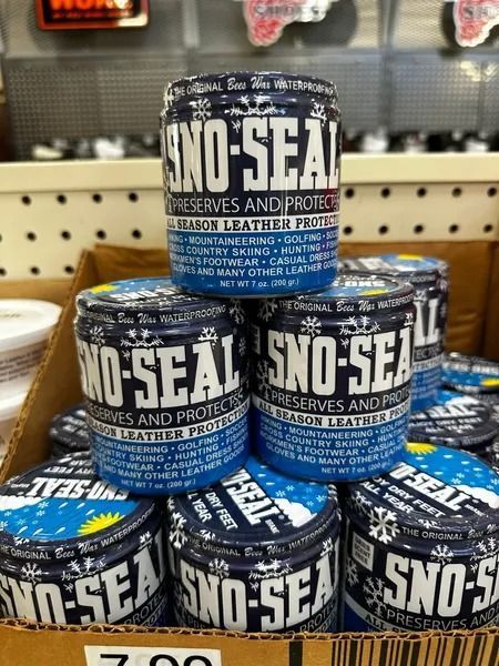 Stacked blue-and-black SNO-SEAL shoe care tins on a store shelf