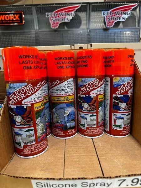 Four red silicone lubricant spray cans displayed on a store shelf with a price tag below.
