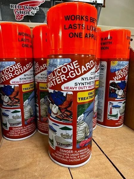 Bright orange silicone water guards and door sealant tubes stacked on a store shelf