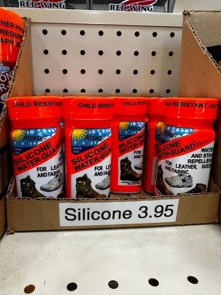 Display of silicone adhesive tubes in a cardboard box with a “Silicone 3.95” price sign.