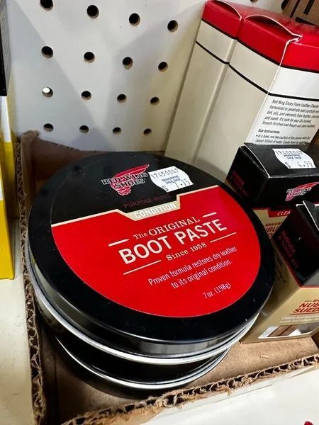 Black tin of Original Boot Paste on a store shelf with red label and nearby shoe care products