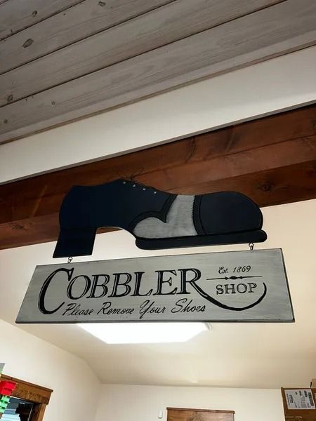 Cobbler Shop sign with a black and gray shoe above it