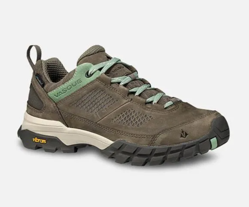 Brown hiking shoe with green laces and rugged black sole, shown in side view on a white background