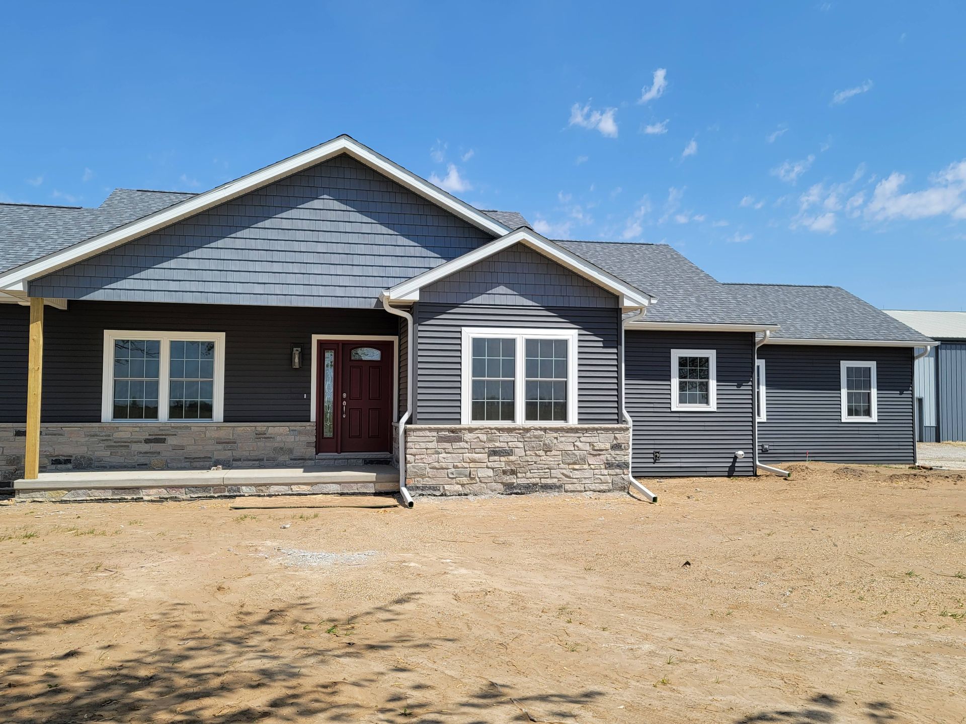 A large house with a lot of windows is sitting on top of a dirt field.
