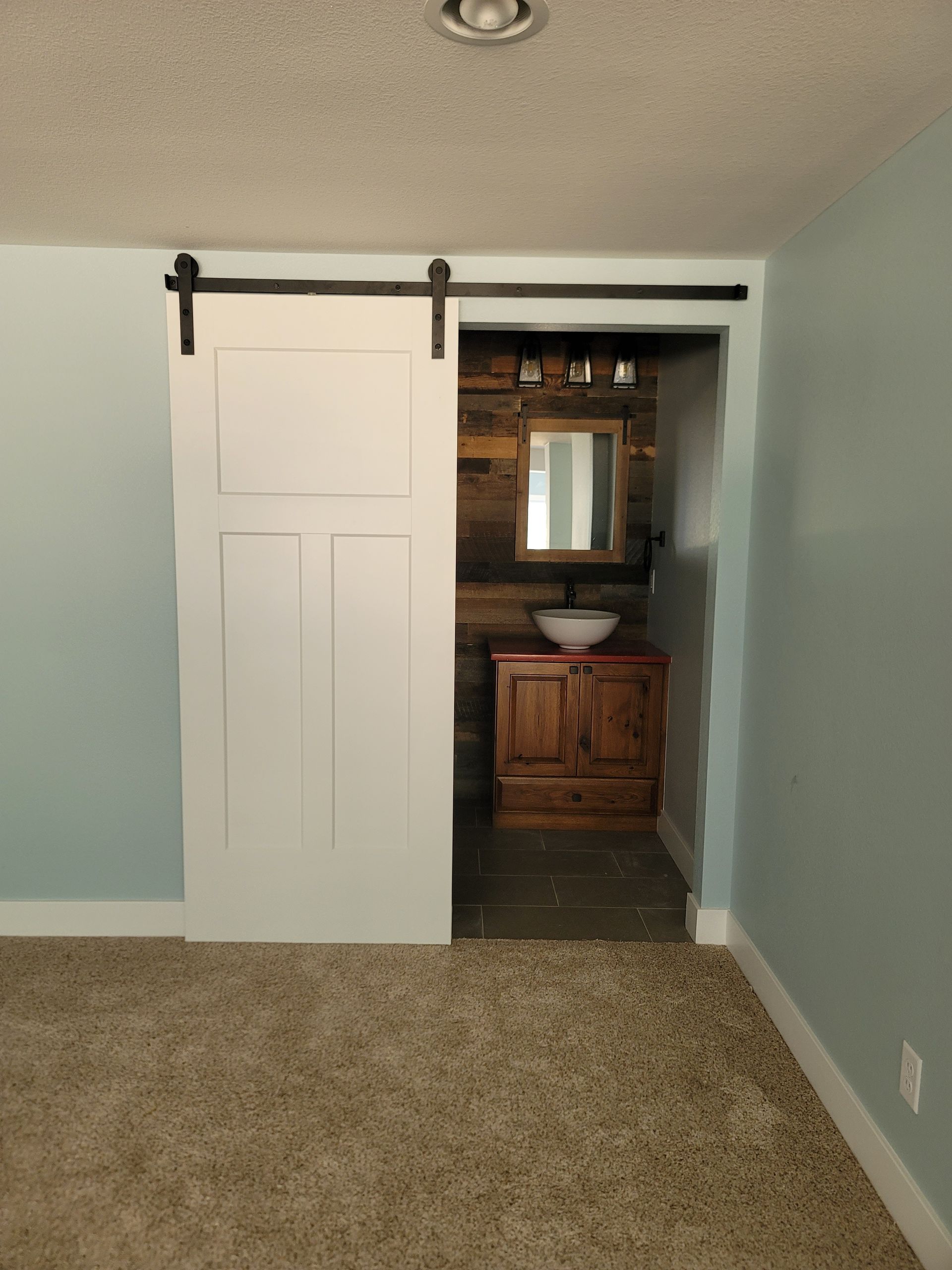 A bathroom with a sliding barn door and a sink.