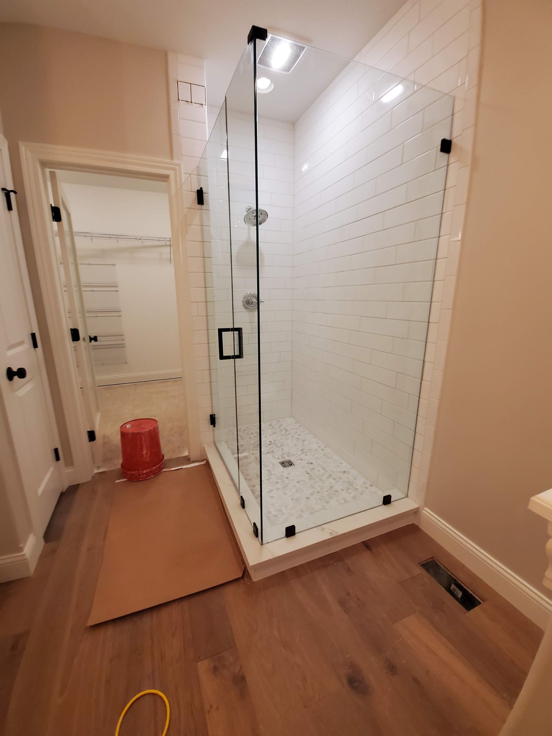 A bathroom with a walk in shower with a glass door.