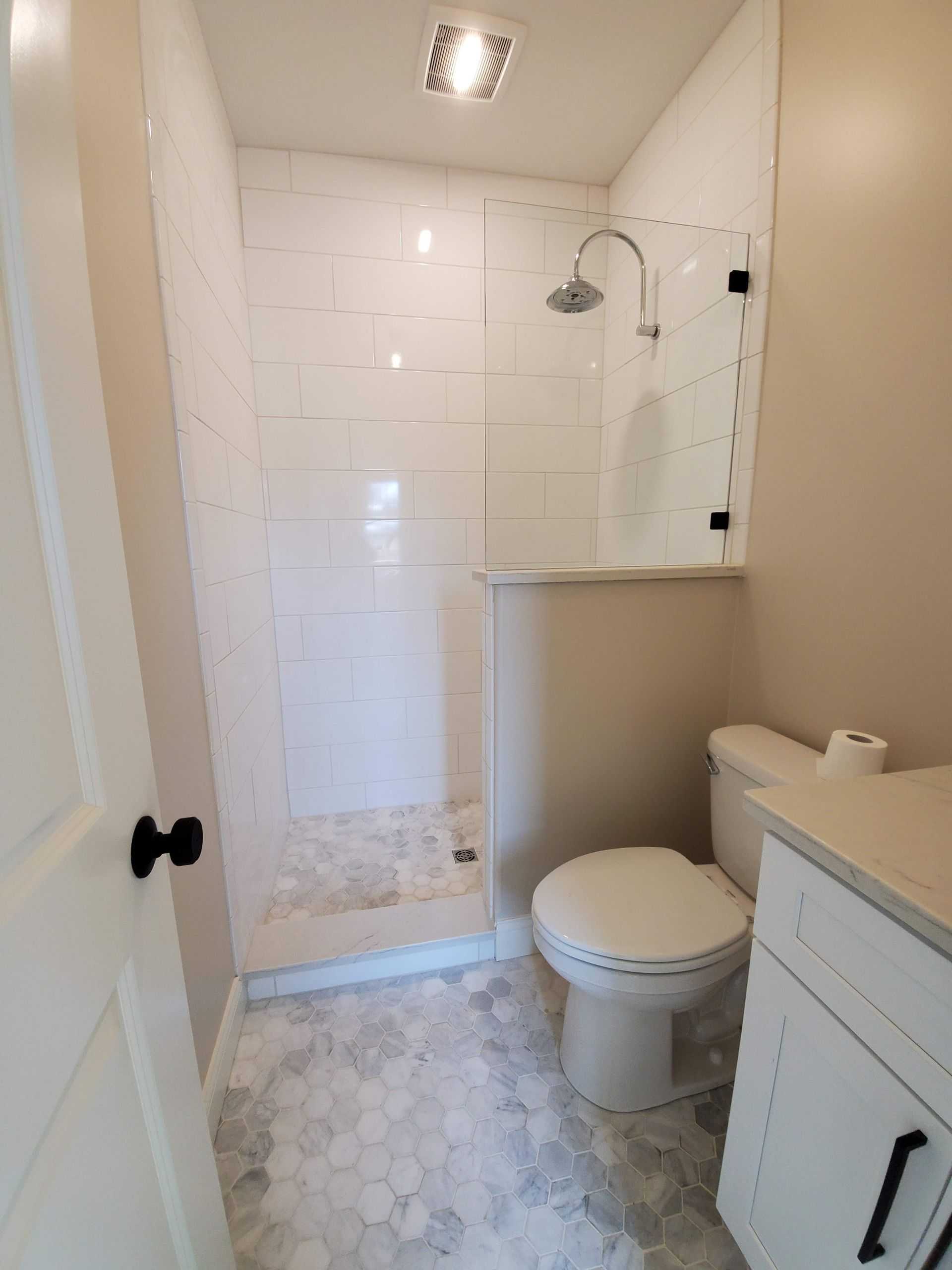 A bathroom with a toilet , sink and shower.