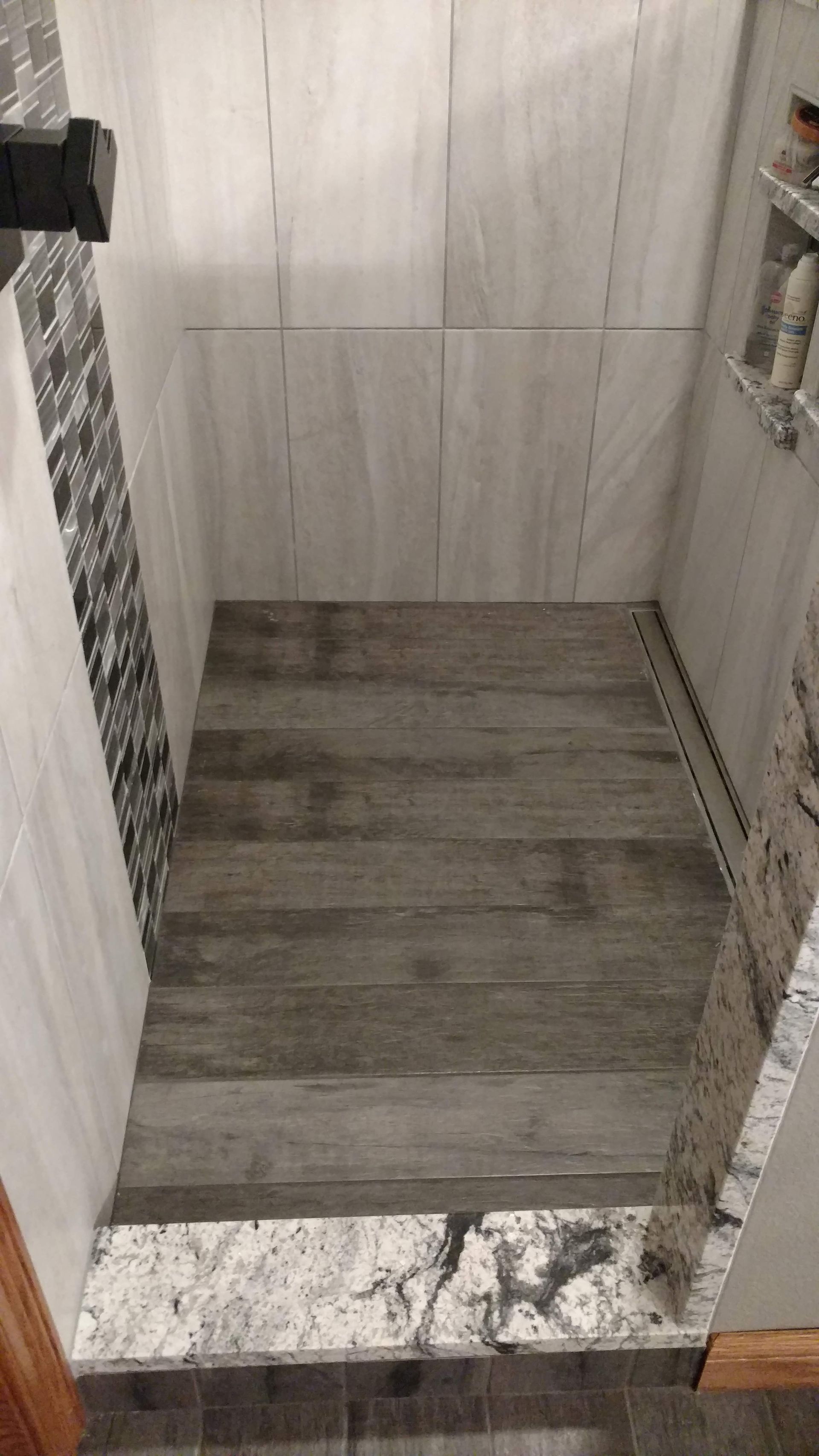 A bathroom with a walk in shower with a wooden floor.