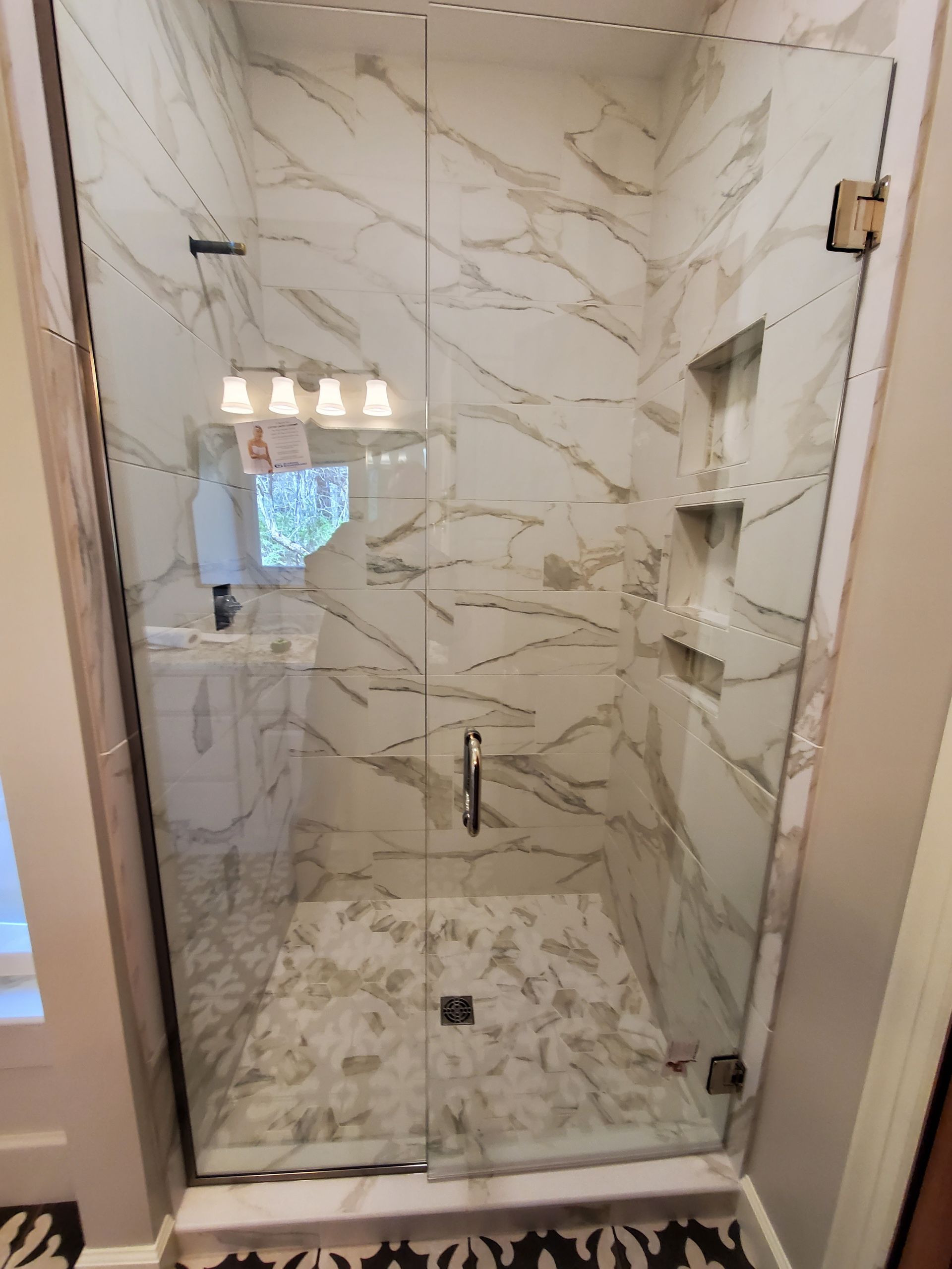 A bathroom with marble tiles and a glass shower door.